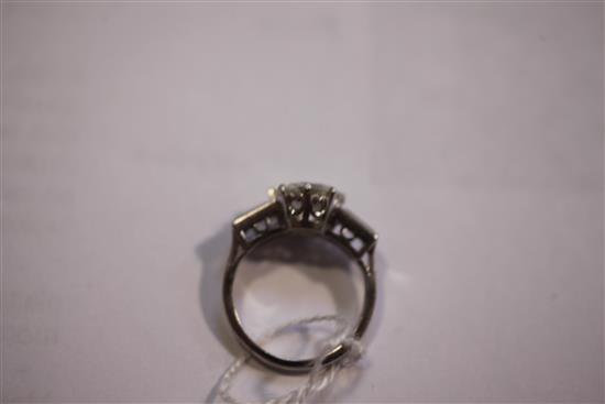 An early to mid 20th century platinum and single stone diamond ring with baguette cut diamond set shoulders, size I.